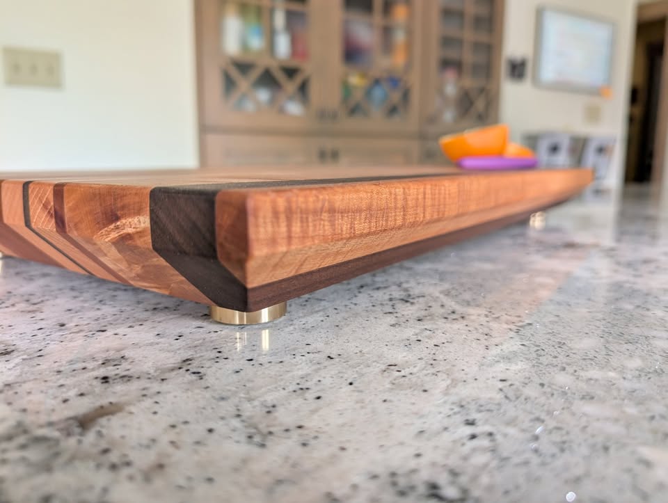 Low-angle view showing the thickness, shaped edge, and metal feet of a cutting board