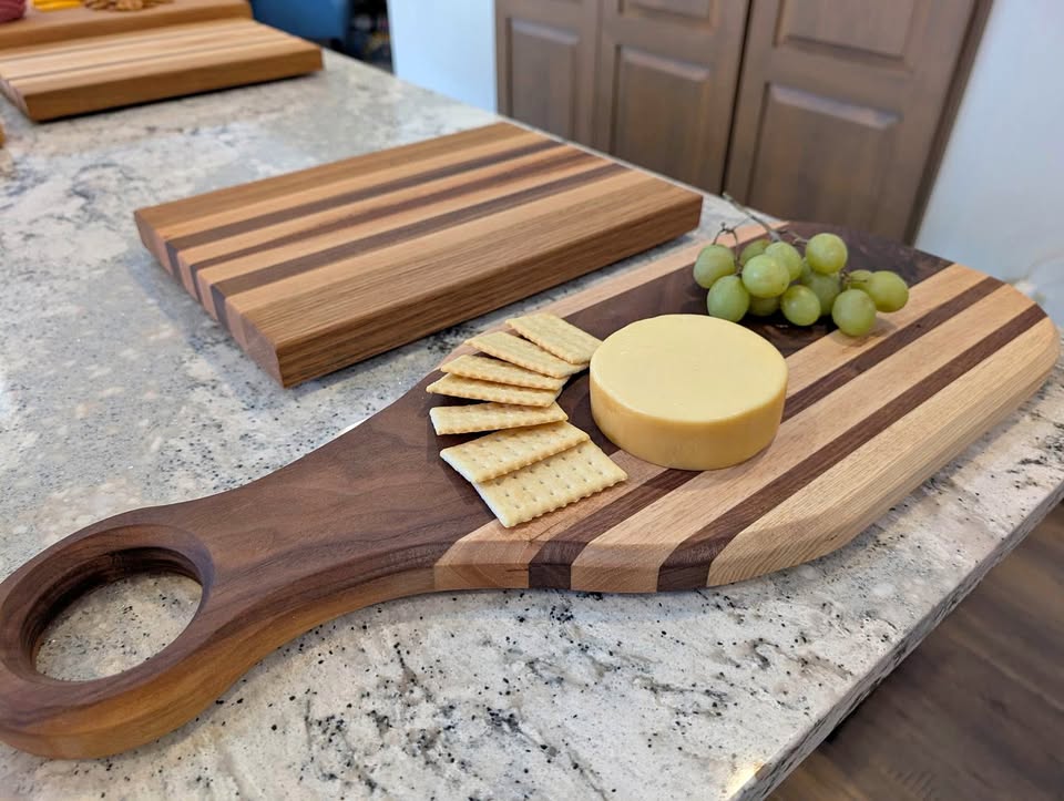 Striped hardwood serving board with handle, cheese, and grapes